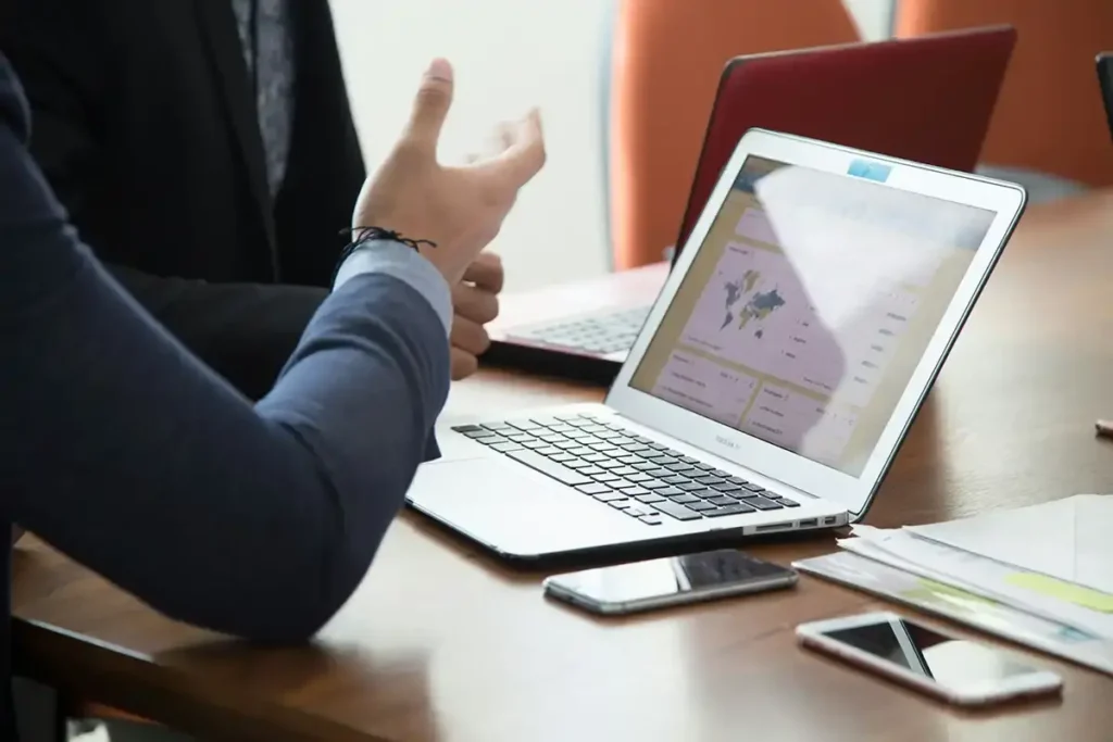 Two professionals discussing the cost of CCTV installation while analyzing data on a laptop.